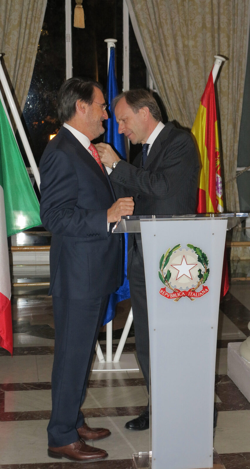 El embajador de Italia impone la condecoración a Jaime Revilla junto a un atril