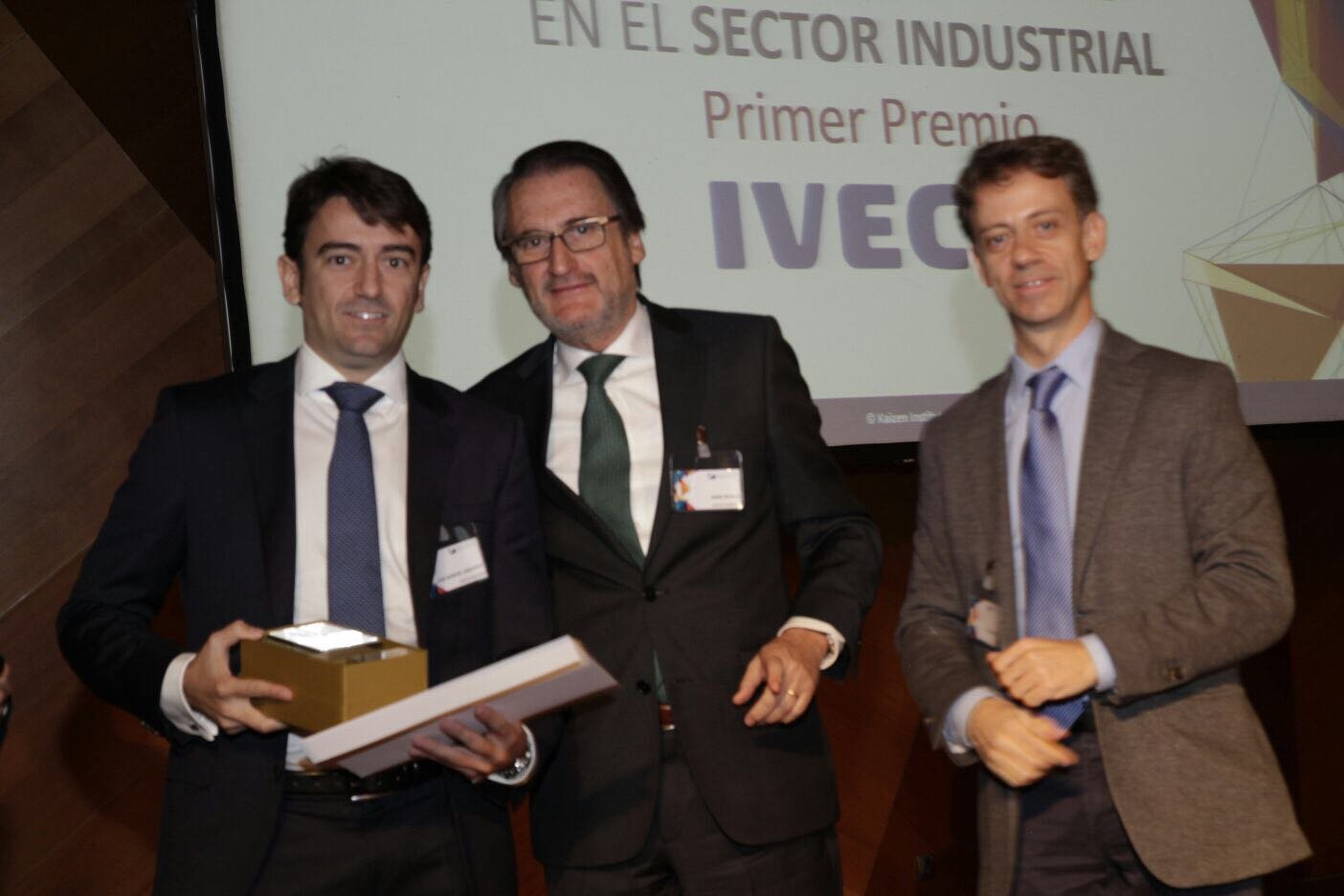 Jaime Revilla posa con dos hombres, uno de ellos con el premio en las manos