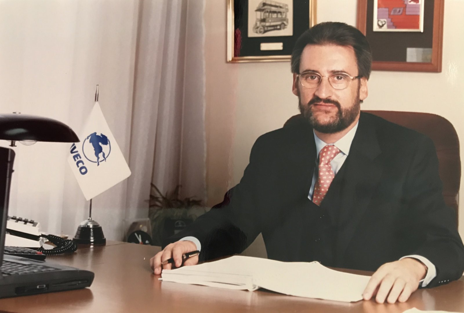 Jaime Revilla en su mesa de trabajo con documentos y un banderín de Iveco